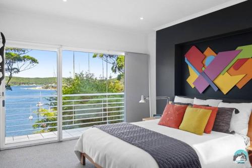 een slaapkamer met een groot bed en een groot raam bij Aircabin - Daleys Point - Waterfront Retreat House in Daleys Point