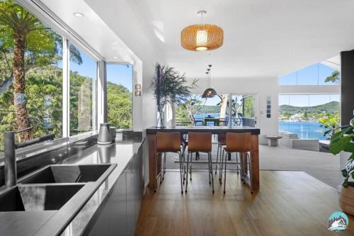 an open kitchen with a table and chairs and large windows at Aircabin - Daleys Point - Waterfront Retreat House in Daleys Point