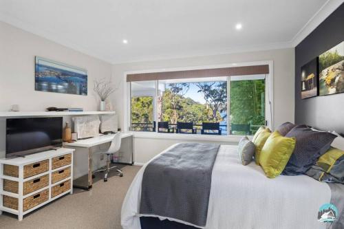 a bedroom with a bed and a desk and a window at Aircabin - Daleys Point - Waterfront Retreat House in Daleys Point