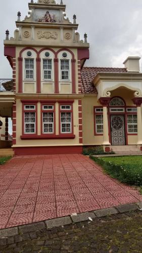 une grande maison avec une allée en briques rouges en face de celle-ci dans l'établissement Villa Eindhoven R9 / 3 Kota Bunga Cipanas Bogor, à Cimacan