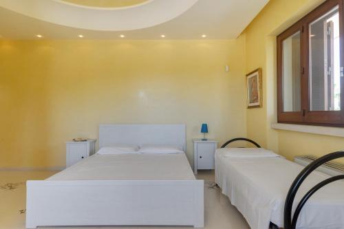 two beds in a room with yellow walls at Relais il Melograno in Arnesano