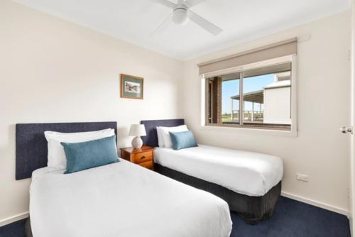 two beds in a room with a window at Marine Cove Resort in Goolwa South