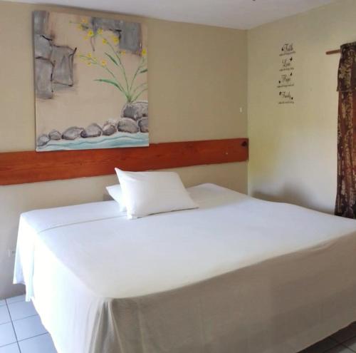 a white bed in a room with a painting on the wall at Highpoint Island Villas in Ocho Rios