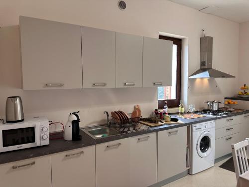 a kitchen with white cabinets and a sink and a microwave at Relais il Melograno in Arnesano