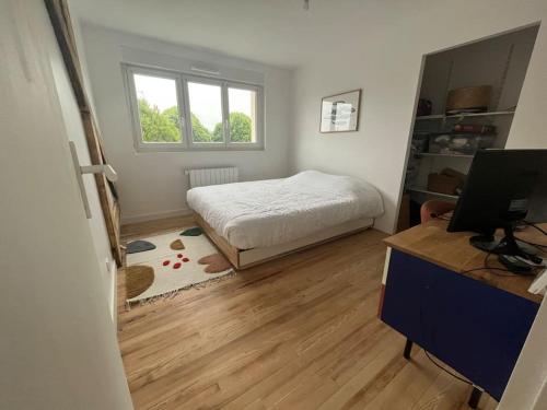 une chambre avec un lit et un bureau avec un ordinateur dans l'établissement Maison familiale au calme, à Lorient