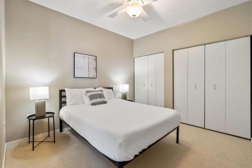 a white bedroom with a bed and a ceiling fan at CozySuites 2BR Mill District pool gym sauna #4 in Minneapolis