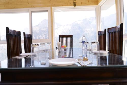una sala da pranzo con tavolo, sedie e finestre di MUSSOORIE ADVENTURE RESORT a Mussoorie
