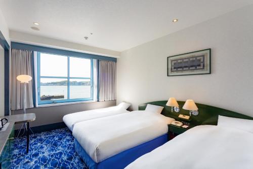 a hotel room with two beds and a window at Premier Hotel Mojiko in Kitakyushu