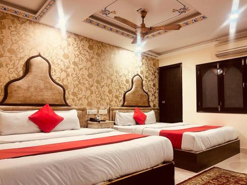 two beds in a hotel room with red pillows at Umed in Jodhpur