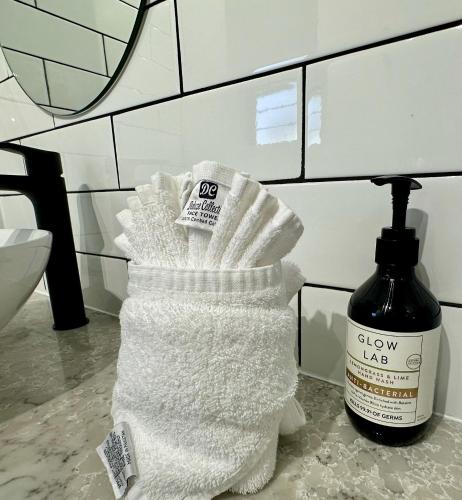 a pile of white towels next to a bottle of clover labouringatio at Luxe Palm Studio Villa - In the heart of Edge Hill in Edge Hill