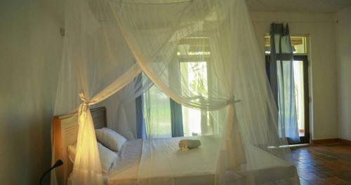 a bedroom with a canopy bed with a large window at Bluewind Resort in Tangalle