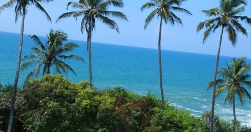 a view of the ocean through palm trees at Bluewind Resort in Tangalle