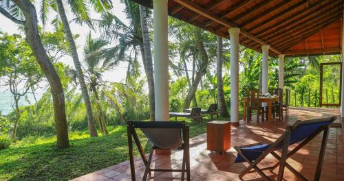 a porch of a house with chairs and a table at Bluewind Resort in Tangalle