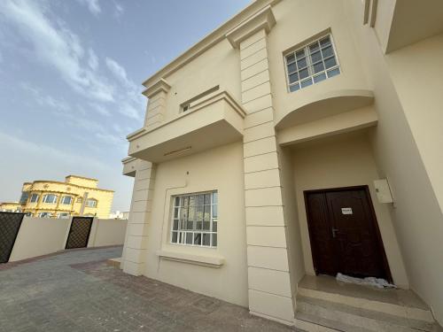 a white building with a door on the side of it at Maison Masirah in Şūr Maşīrah