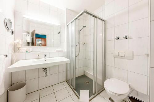 a bathroom with a shower and a toilet and a sink at Hotel Am Moosfeld in Munich