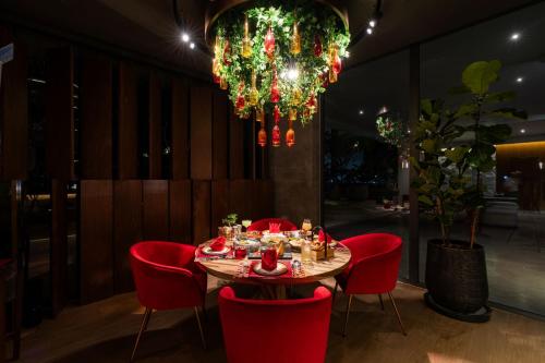 a table with red chairs and a chandelier at La Green Hotel and Residence in Bang Tao Beach
