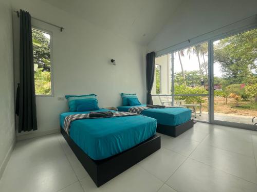 two beds in a room with a window at Mook Ing Lay in Ko Mook