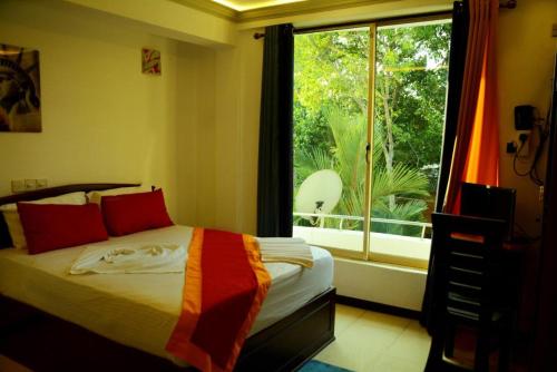 River Top Holiday Resort في Bandaragama: غرفة نوم بسرير ونافذة كبيرة