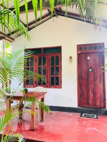a house with a table and a wooden door at Rivinu Place Arugambay in Arugam Bay