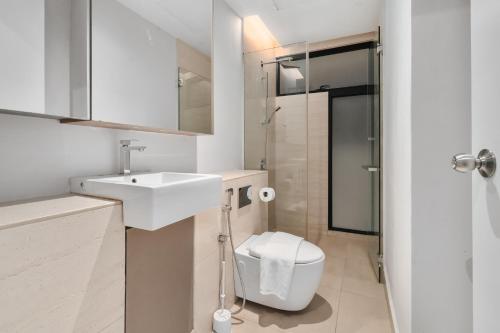 a white bathroom with a sink and a toilet at Lumi Tropicana by Nexus Homes in Petaling Jaya