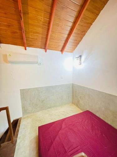 a room with a red bed and wooden ceilings at Rivinu Place Arugambay in Arugam Bay