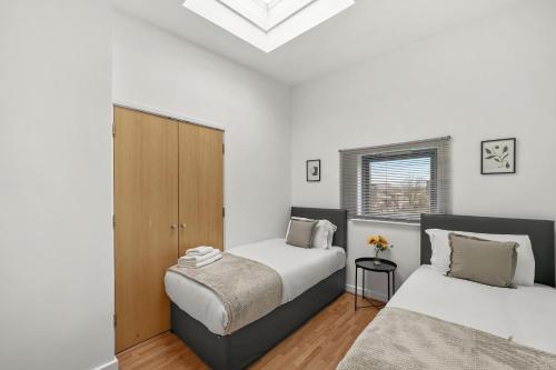twee bedden in een kamer met witte muren bij Livestay - Two Bed London Apt with Balcony in Colindale