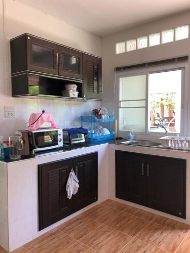a kitchen with black and white cabinets and a sink at Thanid House in Ban Nai Khlong