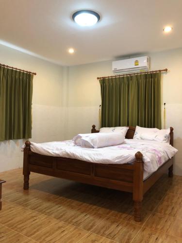 a bedroom with a large bed with green curtains at Thanid House in Ban Nai Khlong