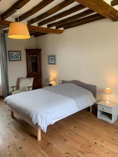 une chambre avec un grand lit blanc et une chaise dans l'établissement Maison à louer, à Noron-la-Poterie