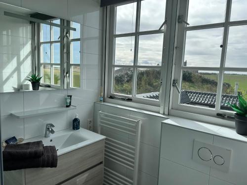 a white bathroom with windows and a sink at Landhuis Mariëtta in De Koog