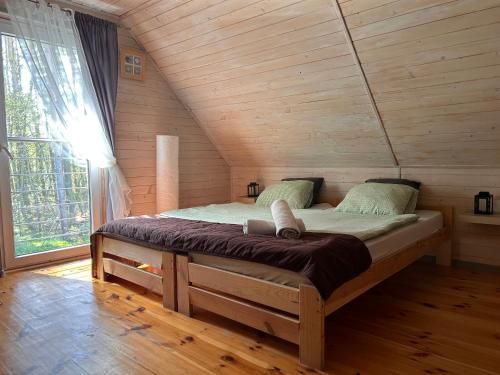 a bed in a log cabin with a large window at Resort EDEN domki, apartamenty i pokoje in Jastrzębia Góra