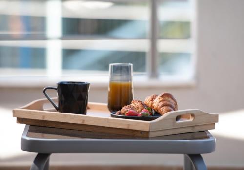 a tray with a glass of juice and a plate of croissants and coffee at StayInn Luxury Apartments in Nea Kalikratia