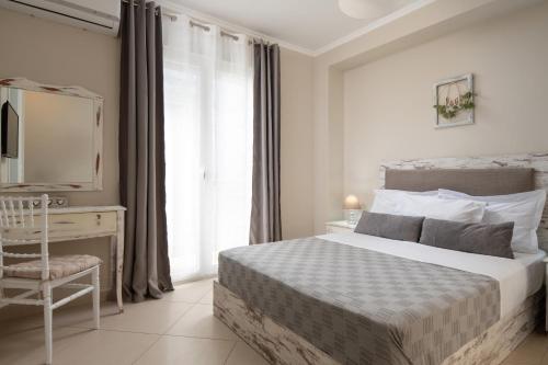 a bedroom with a bed and a desk and a window at StayInn Luxury Apartments in Nea Kalikratia