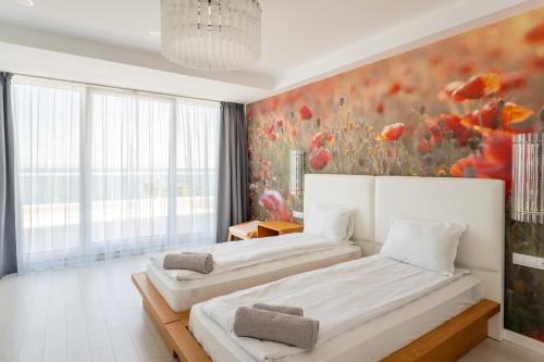 two beds in a room with a painting on the wall at The LODGE Summer Apartments Sozopol in Sozopol