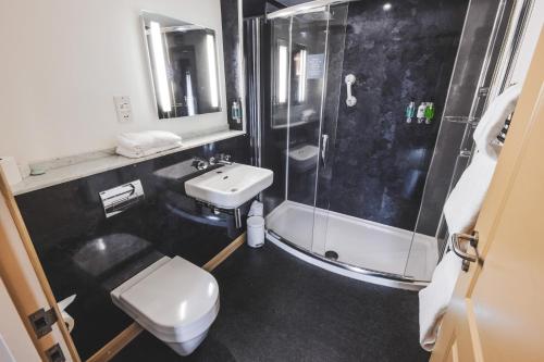 a bathroom with a shower and a toilet and a sink at The Auberge in Yaxley