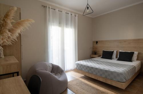 1 dormitorio blanco con 1 cama y 1 silla en StayInn Luxury Apartments en Nea Kallikratia