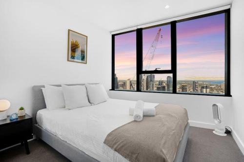 een slaapkamer met een bed en een groot raam bij NEW Waterfront Living With Sublime Views 2B1B in Melbourne