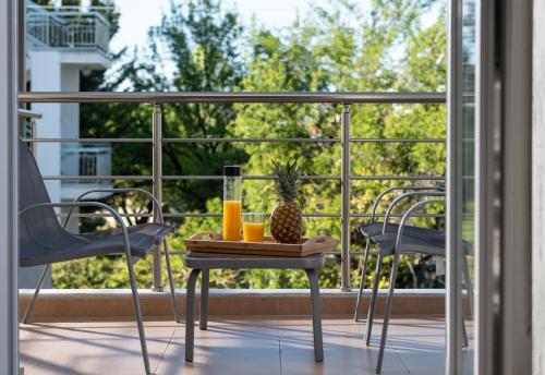 a table with a pineapple and drinks on a balcony at StayInn Luxury Apartments in Nea Kalikratia