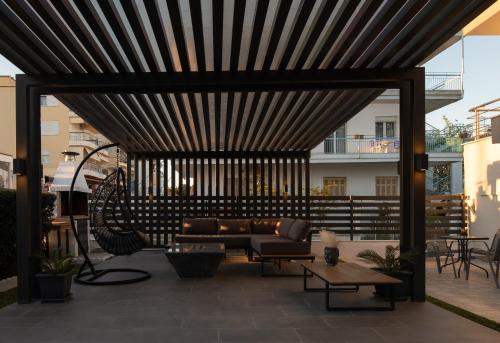 acovered patio with a couch and a table at StayInn Luxury Apartments in Nea Kalikratia