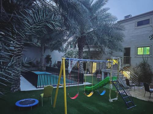 un cortile con parco giochi con scivolo e palme di Glory Resort a Al Ahsa