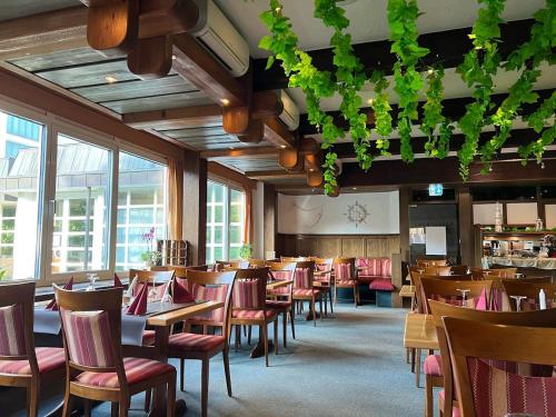 una sala da pranzo con tavoli, sedie e finestre di G&P Housing Apartments mit Küche & Balkon & HighSpeed Internet- Comfort ad Altensteig