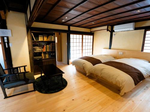 1 dormitorio con 1 cama grande y 1 silla en 姫路城の奥座敷　築400年の宿 鐵十郎（登録文化財）, en Fukusaki