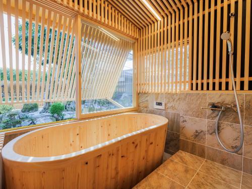 baño con bañera de madera y ventana en 姫路城の奥座敷　築400年の宿 鐵十郎（登録文化財）, en Fukusaki