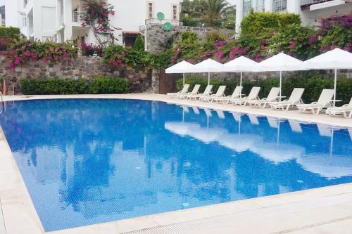 uma grande piscina com cadeiras brancas e guarda-sóis em Seaview (Sunset & Greek-Islands) Luxury Apartment em Bodrum City