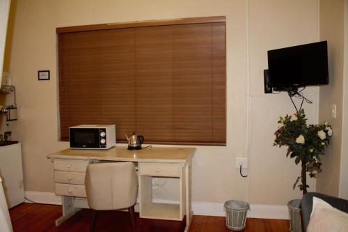 a room with a desk with a microwave and a window at Lockerbie Lodge in Vryburg