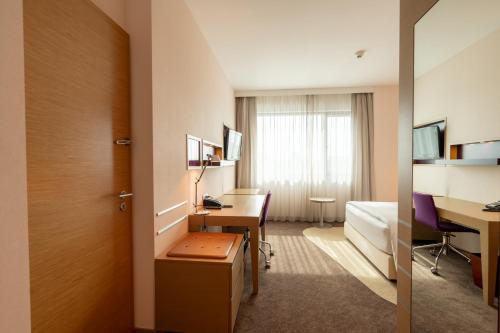a hotel room with a desk and a room at DoubleTree by Hilton Oradea in Oradea