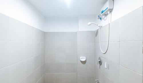 a white bathroom with a shower with a shower head at RedDoorz near SM City Muntinlupa in Manila
