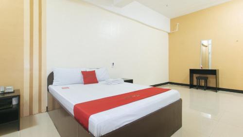 um quarto com uma cama grande e um cobertor vermelho em RedDoorz near SM City Muntinlupa em Manila