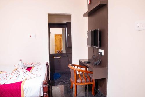 - une chambre avec un lit, un bureau et une télévision dans l'établissement MUTHU RESIDENCY, à Thanjavur