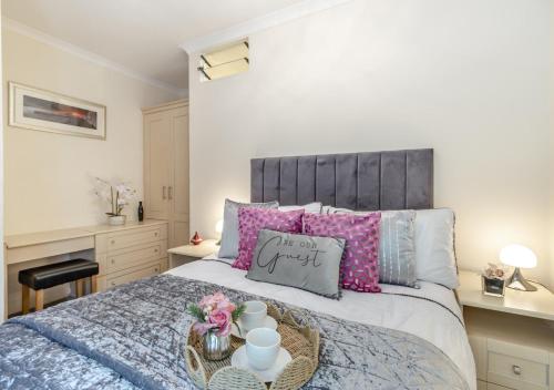 1 dormitorio con 1 cama grande con almohadas rosas en Seashells, en Saundersfoot